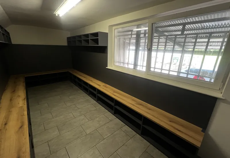 Futbalová šatňa s dubovo-čiernymi šatňovými boxmi a lavicami